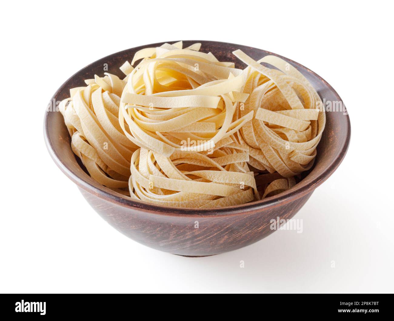 Ungekochte Tagliatelle Pasta in Keramikschale isoliert auf weißem Hintergrund mit Schneideweg Stockfoto