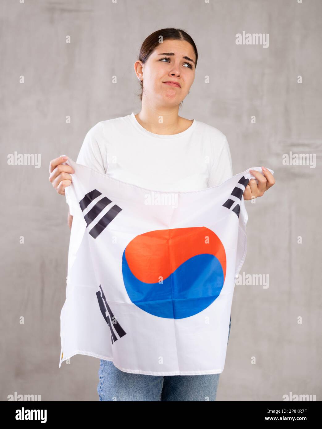 Frustrierte junge Frau mit südkoreanischer Flagge an der grauen Wand Stockfoto