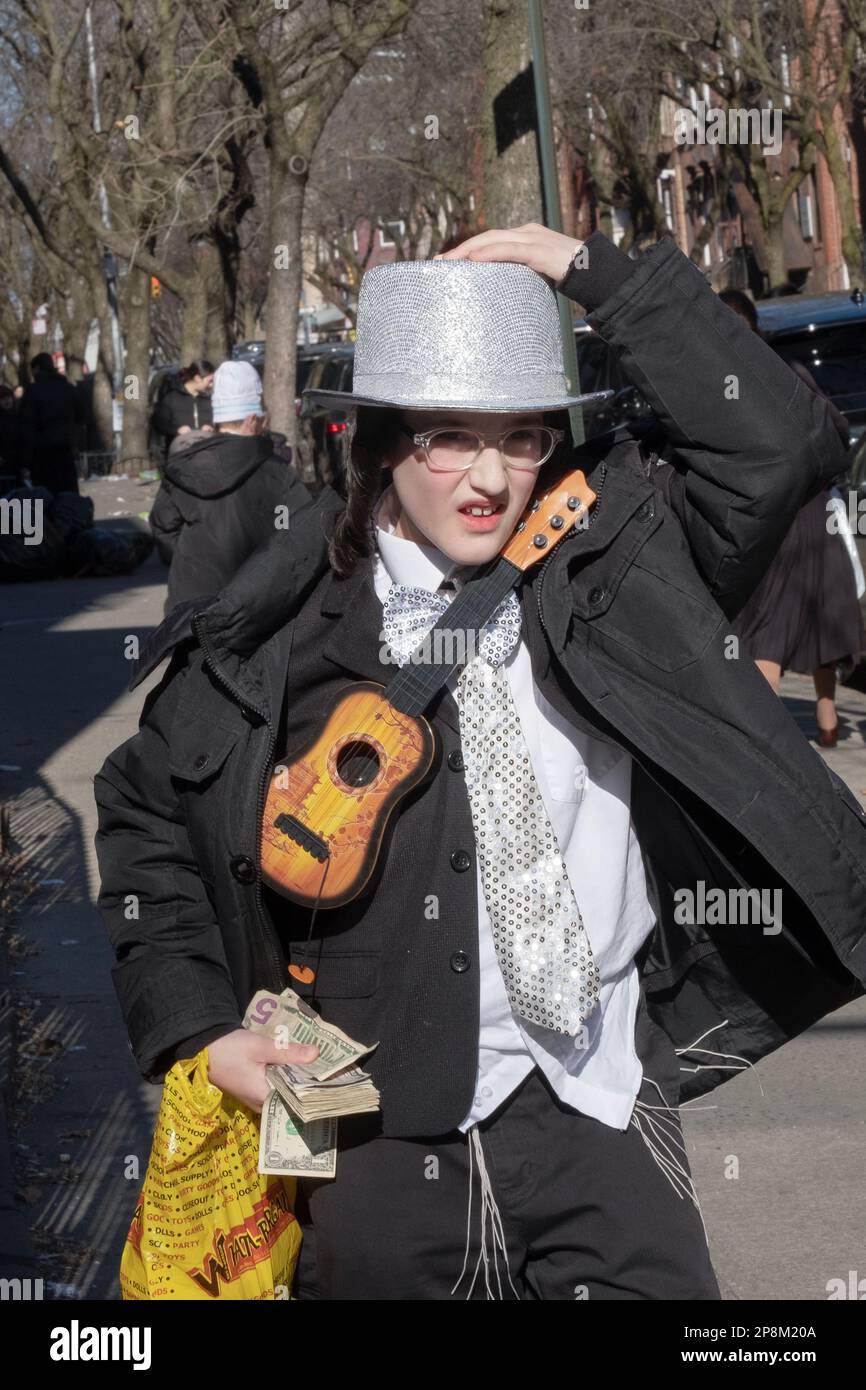 PURIM 2023, 2 RITUALE. KOSTÜME UND WOHLTÄTIGKEITSVERANSTALTUNGEN. Ein orthodoxer jüdischer Junge in einem Kostüm sammelt Wohltätigkeit für die Armen. In Brooklyn, New York. Stockfoto