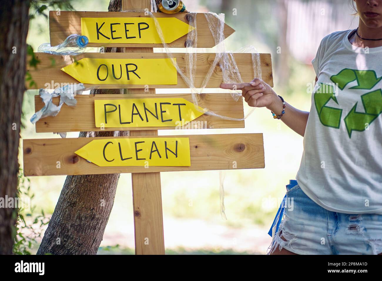 Junger Aktivist, der auf dem Holzbrett zeigt und sagt: "Halte unseren Planeten sauber." Freiwillige in der Natur sammeln Müll auf. Umweltbewusstsein, Grün, Lifestyle-Konzept Stockfoto