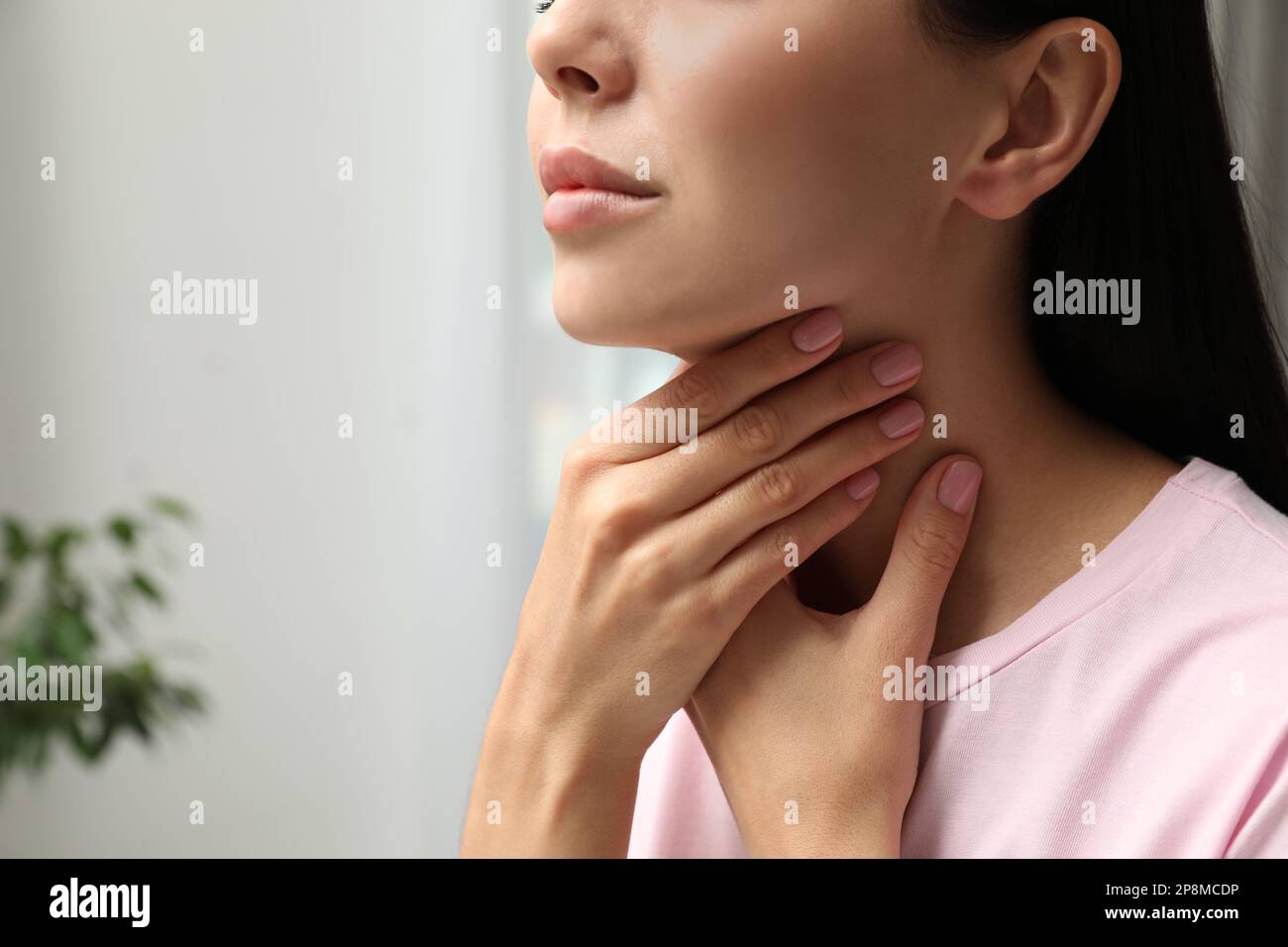 Junge Frau, die sich in geschlossenen Räumen einer Schilddrüsen-Selbstuntersuchung unterzieht, Nahaufnahme. Platz für Text Stockfoto