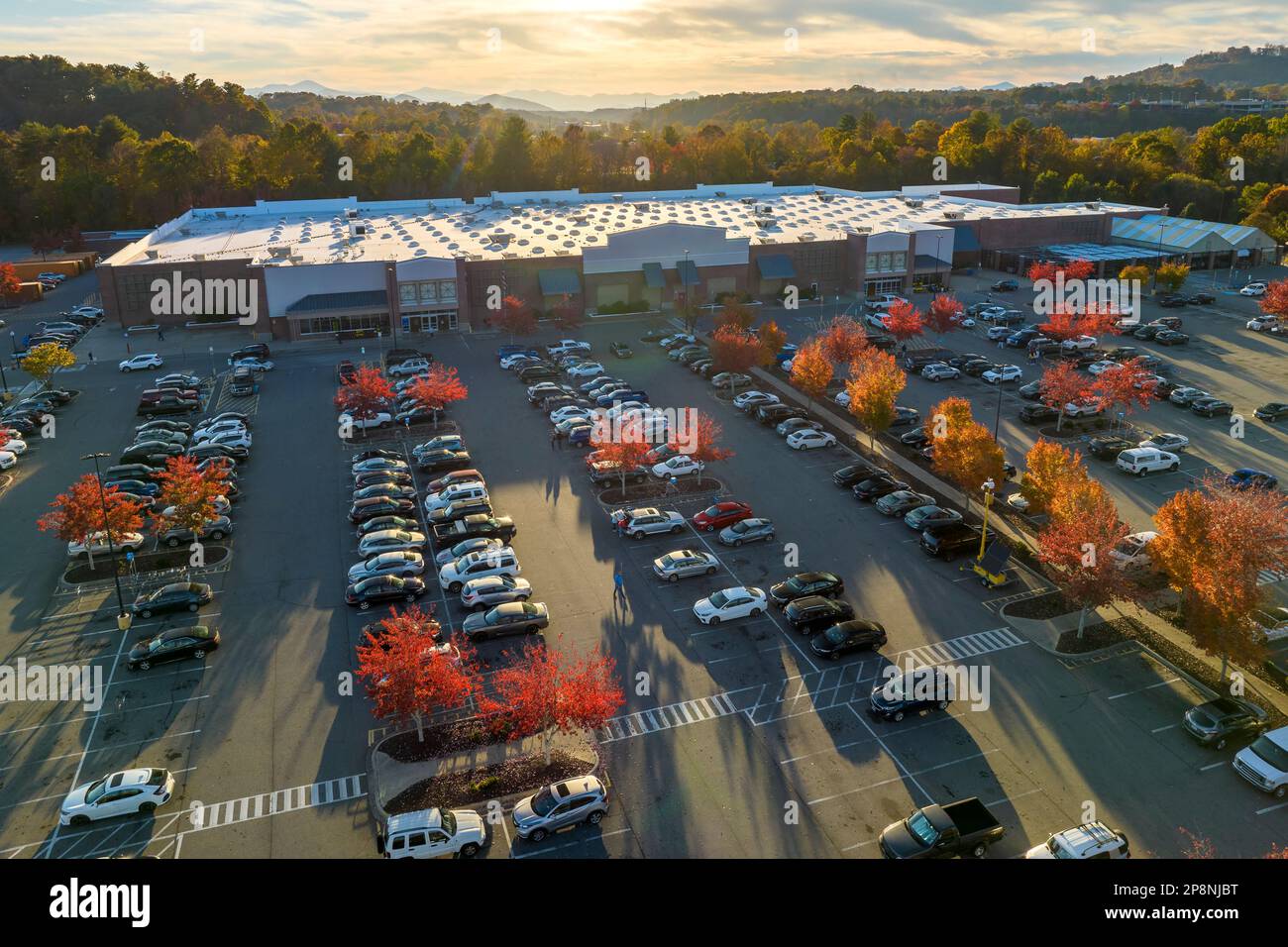 Von oben sehen Sie viele Autos, die auf einem Parkplatz vor einem Einkaufszentrum geparkt sind. Konsumerismus und Marktwirtschaft. Stockfoto
