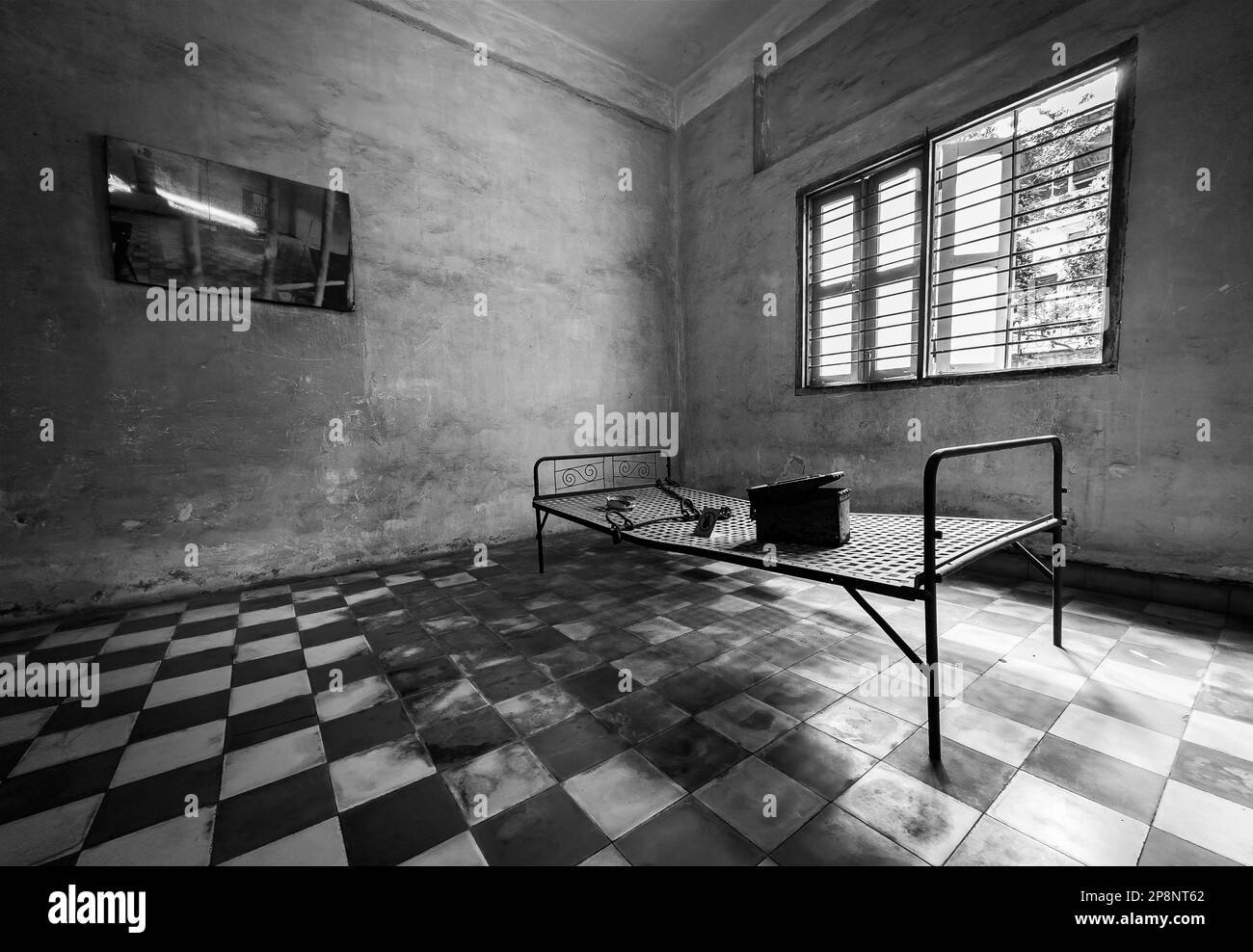 Ein Bettgestell aus Stahl in einer Folterzelle, die aus einem ehemaligen Klassenzimmer in Tuol Sleng umgebaut wurde, oder S-21 Folter- und Völkermord-Museum in Phnom Penh, Kambodscha Stockfoto