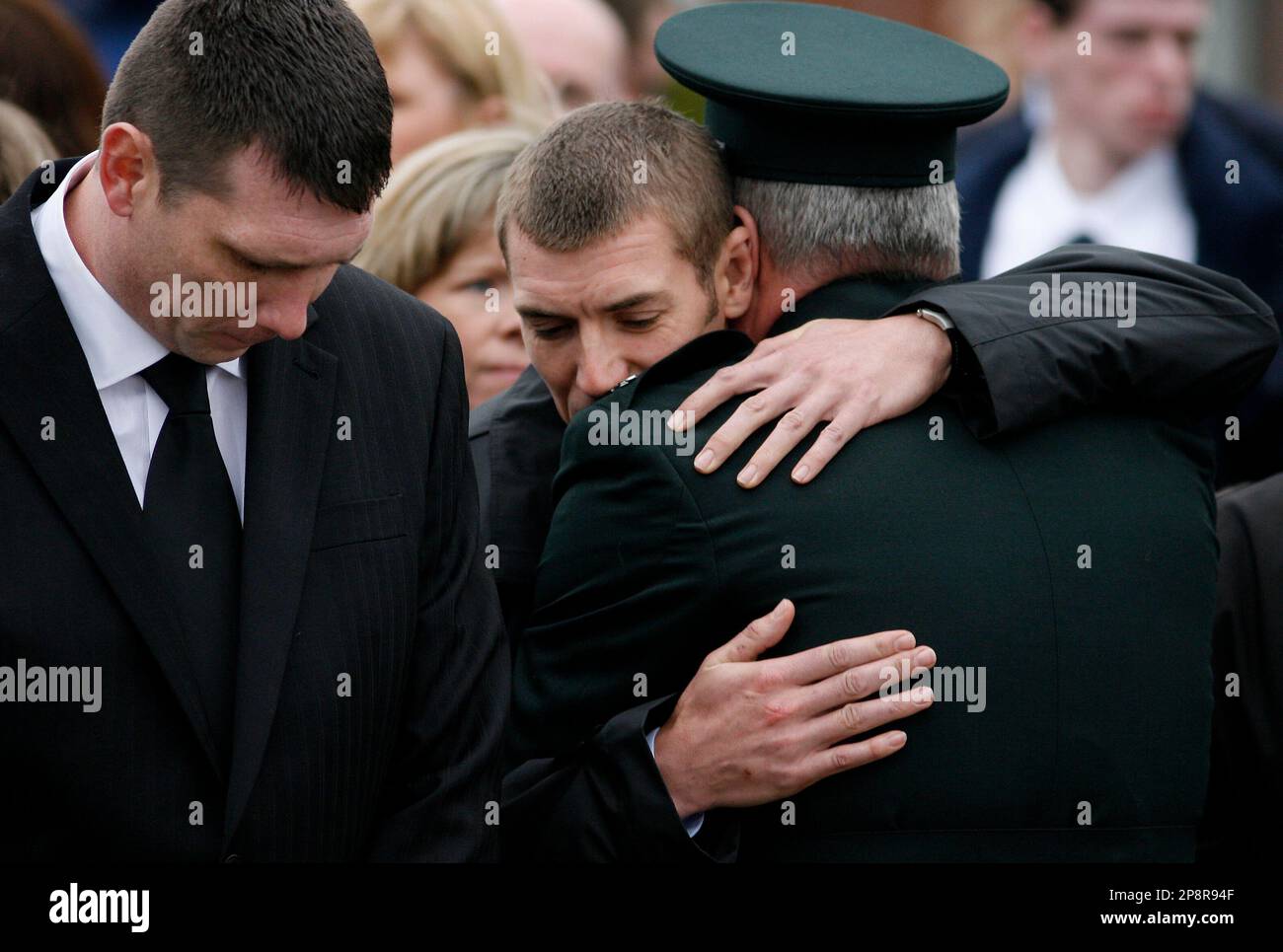 People comfort each other at the funeral of Police Service of Northern