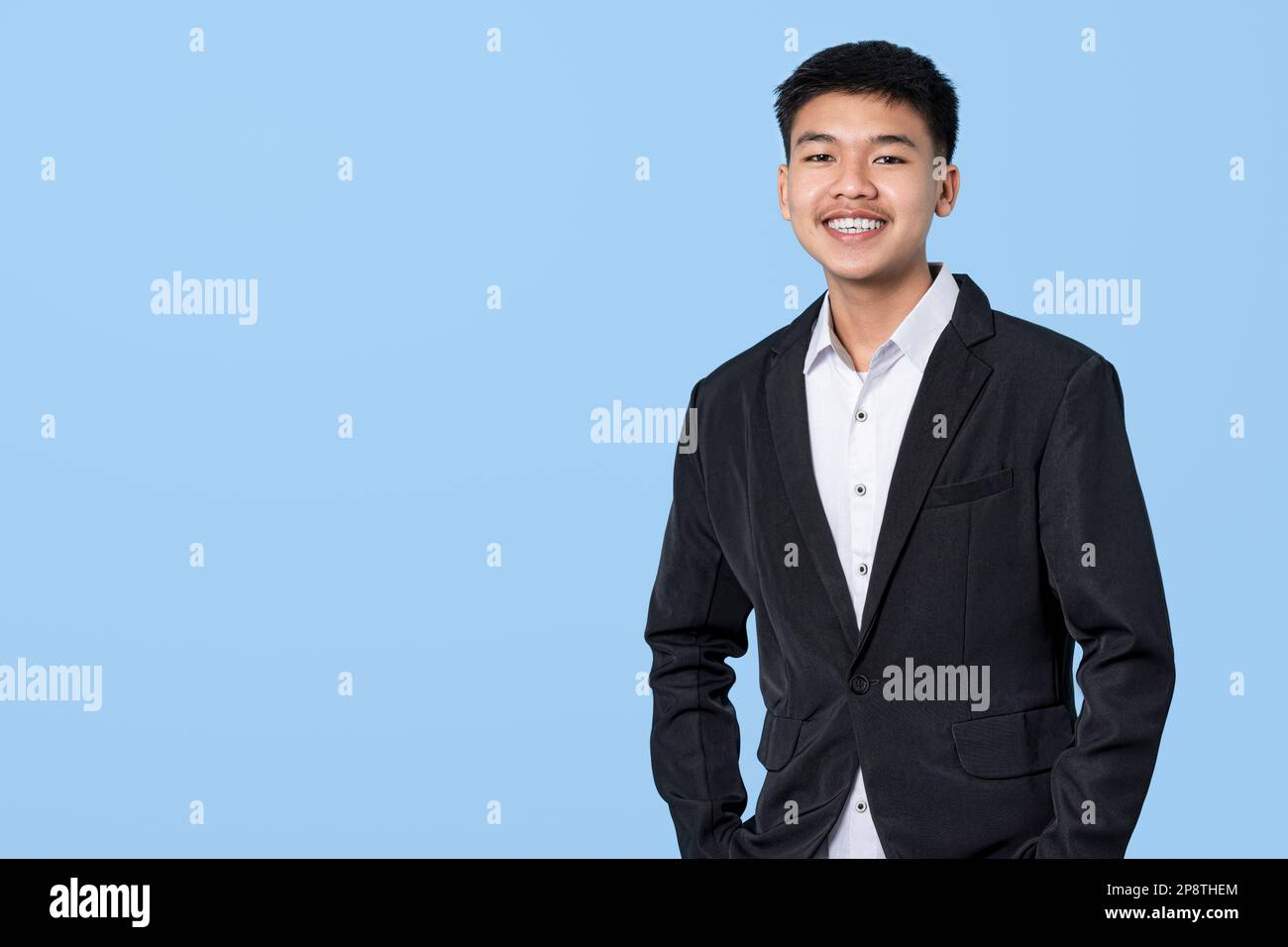 Junger, gutaussehender asiatischer Geschäftsmann, der selbstsicher lächelt, isoliert auf blauem Hintergrund. Konzept für Geschäftsleute. Stockfoto