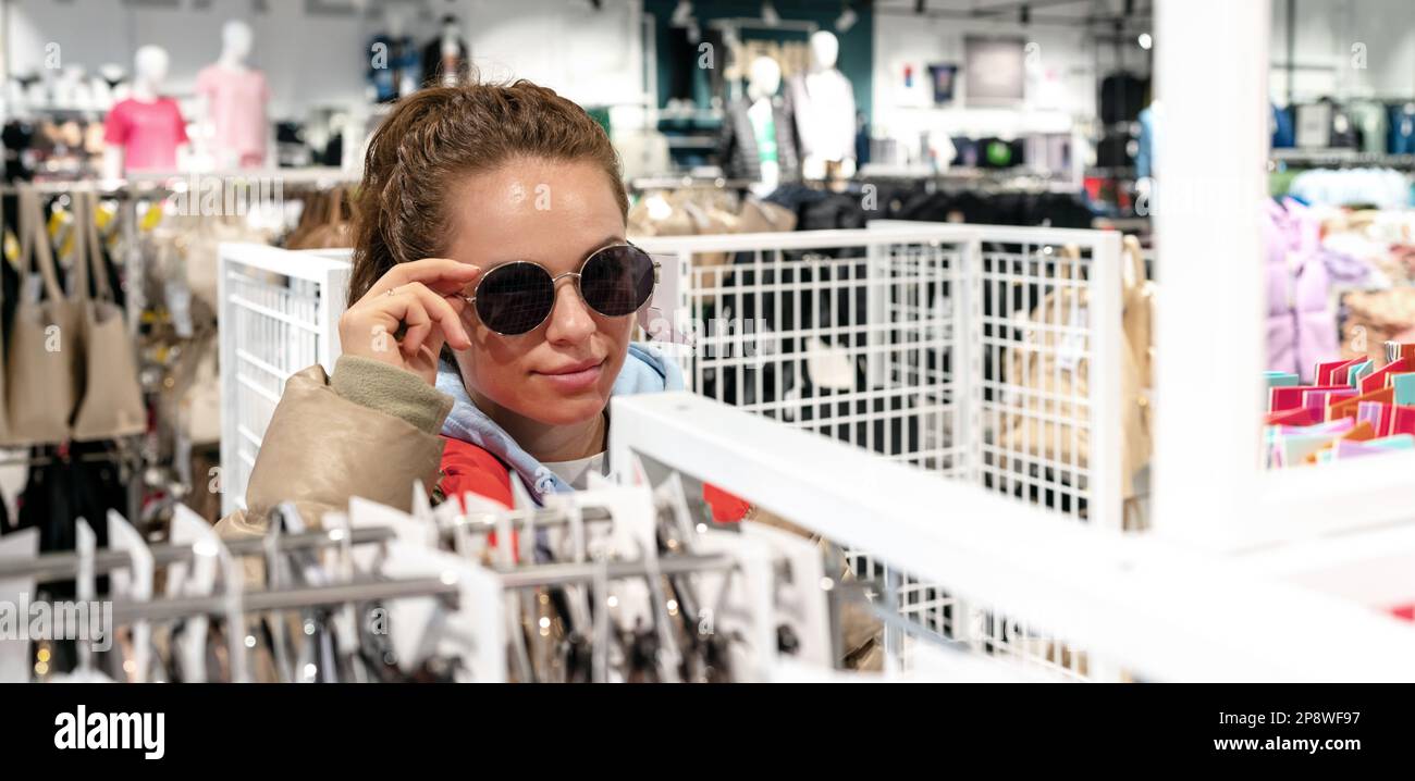 Frau probiert Sonnenbrille im Geschäft für Kleidung und Accessoires an. Stockfoto