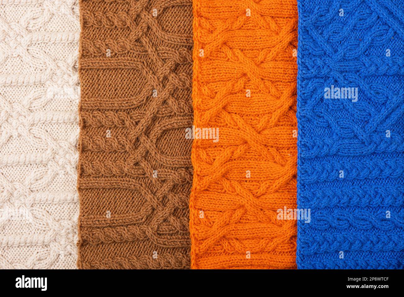 Gestrickter Hintergrund in Blau, Orange, Braun und Beige. Großer Strickstoff mit Muster. Nahaufnahme einer Strickdecke. Banner Stockfoto