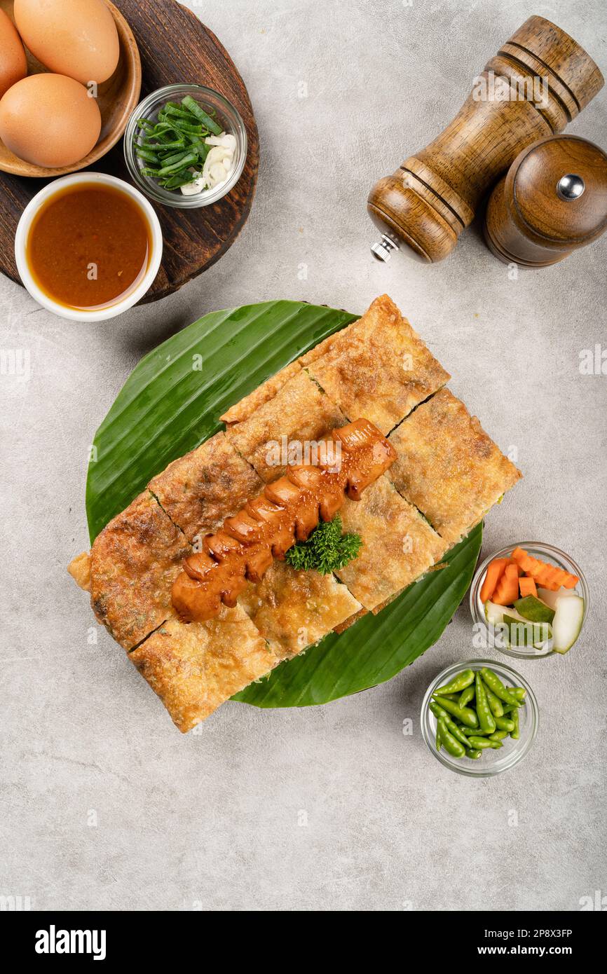 Martabak Telur ist indonesisches Street Food, hergestellt aus herzhaftem gebratenem Gebäck in der Pfanne, gefüllt mit Ei, Frühlingszwiebeln, Fleisch, Wurst, Gewürzen und Käse. Stockfoto