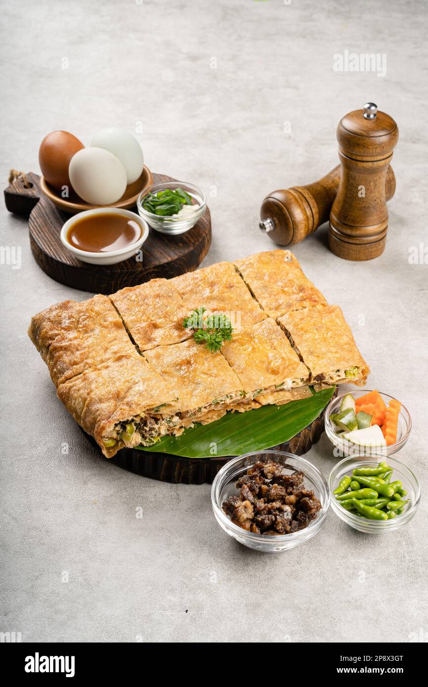 Martabak Telur ist indonesisches Street Food, hergestellt aus herzhaftem gebratenem Gebäck in der Pfanne, gefüllt mit Ei, Frühlingszwiebeln, Fleisch, Wurst, Gewürzen und Käse. Stockfoto