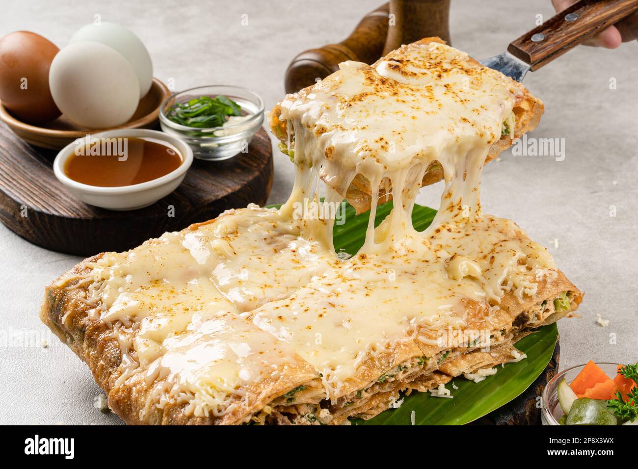 Martabak Telur ist indonesisches Street Food, hergestellt aus herzhaftem gebratenem Gebäck in der Pfanne, gefüllt mit Ei, Frühlingszwiebeln, Fleisch, Wurst, Gewürzen und Käse. Stockfoto