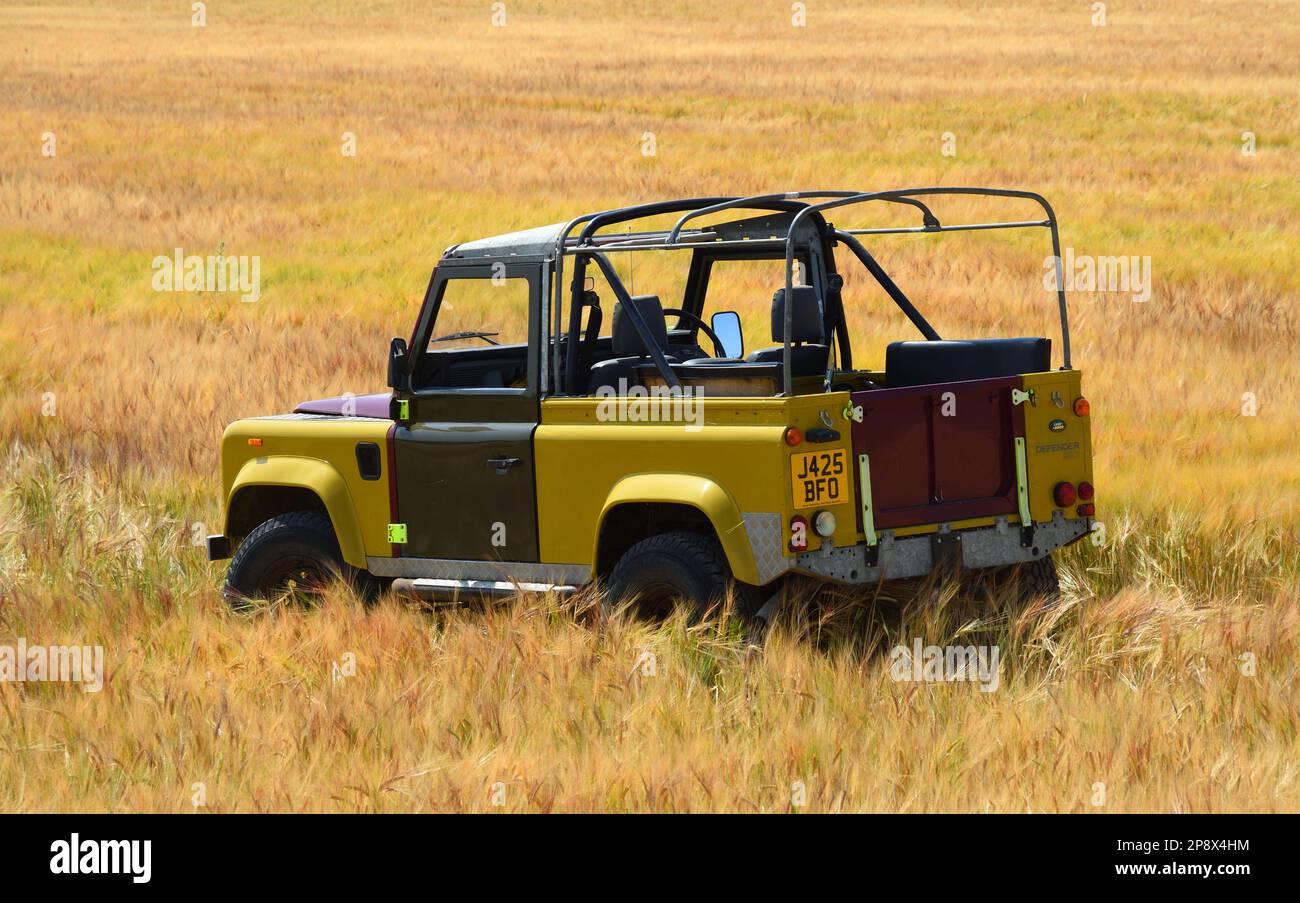 BLAKENEY, NORFOLK, ENGLAND - 13. JULI 2022: Land Rover Defender parkt auf einem Weizenfeld Stockfoto