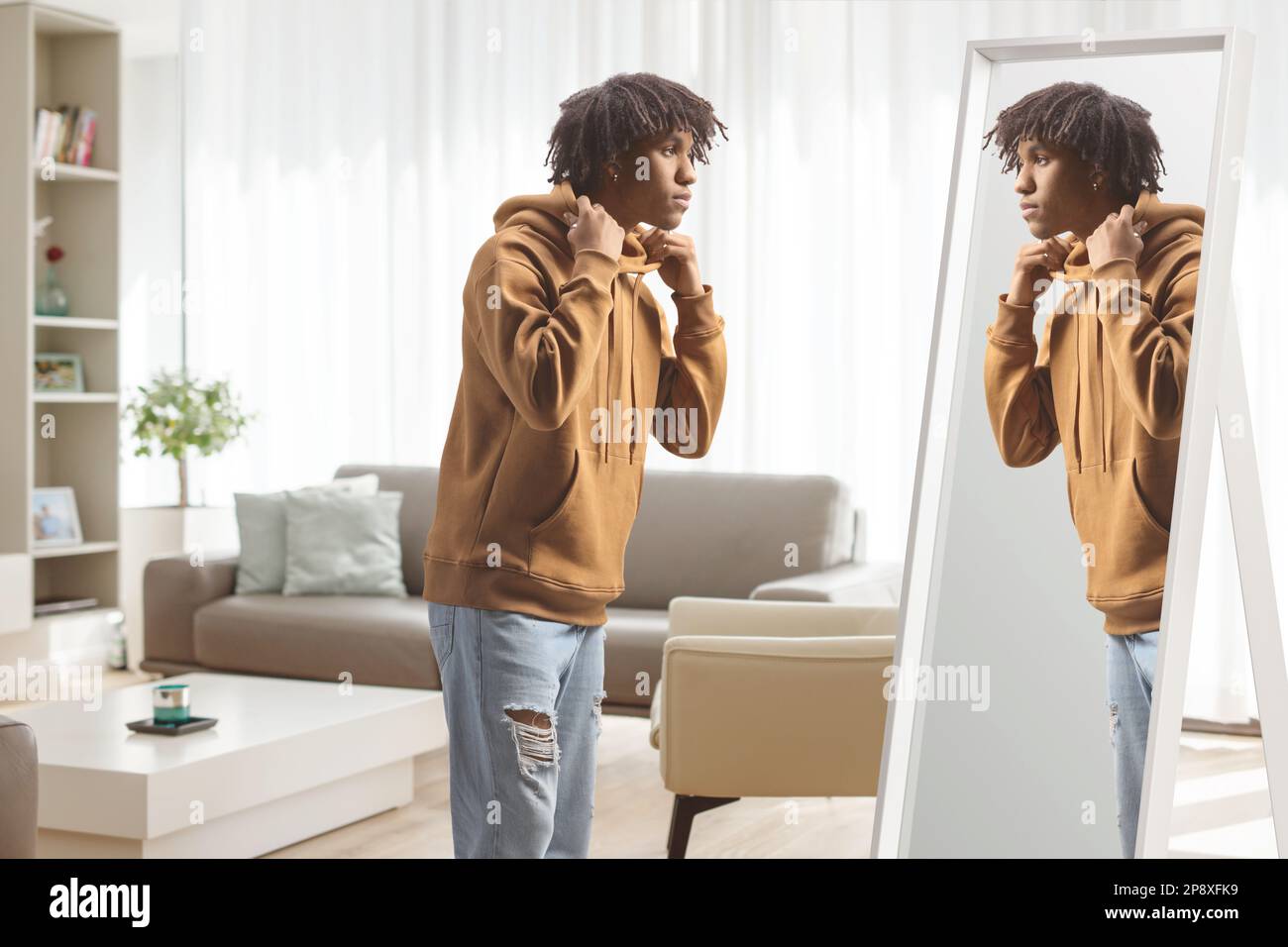 Ein junger afroamerikanischer Mann, der zu Hause vor einem Spiegel steht Stockfoto