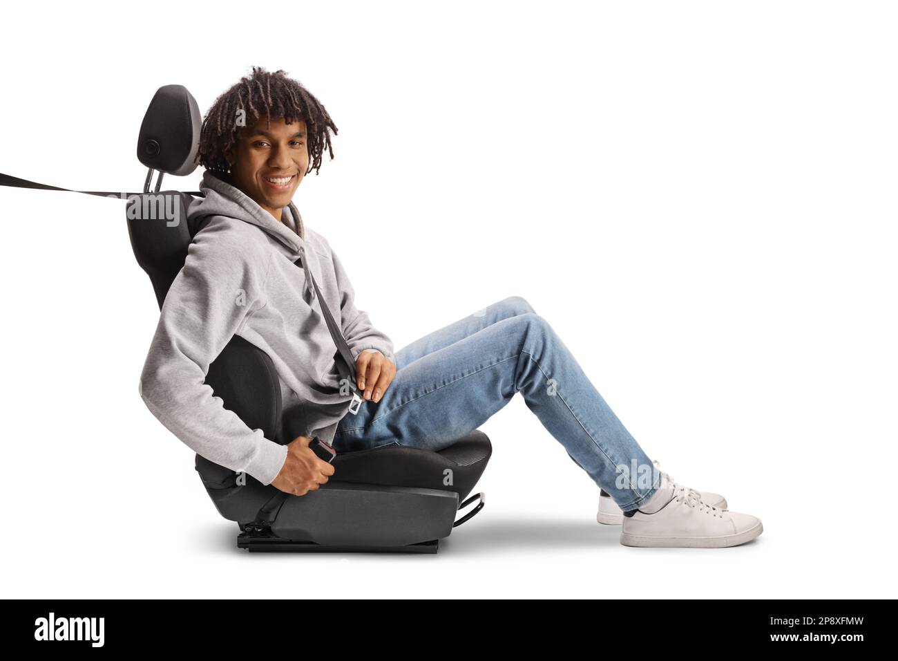 afroamerikanischer junger Mann, der auf einem Autositz sitzt, mit einem Sicherheitsgurt angeschnallt ist und isoliert auf weißem Hintergrund lächelt Stockfoto