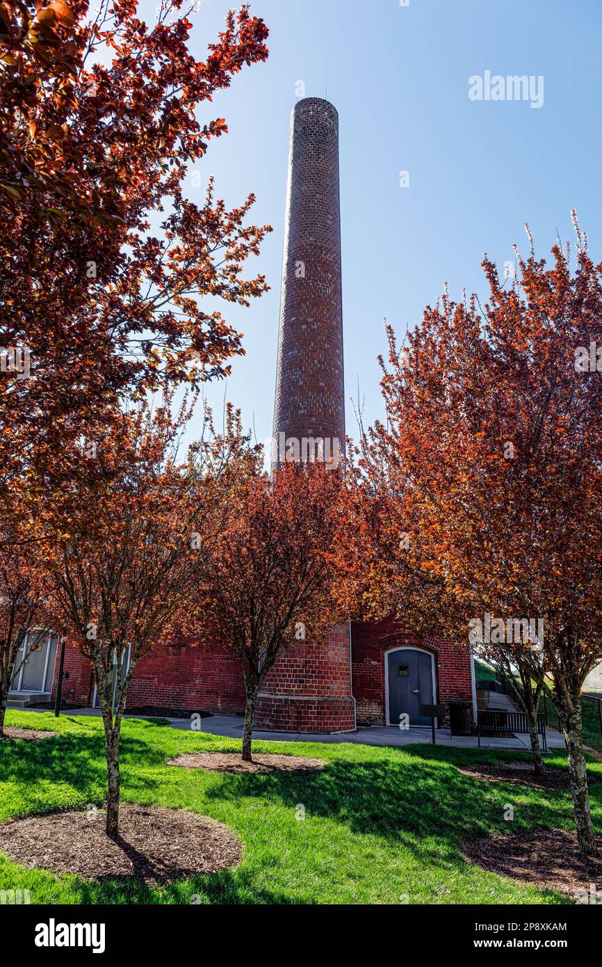 CHARLOTTE, NC-5. MÄRZ 2023: Bezirk Noda. Blick auf den Schornstein im Lofts at Noda Mills, eingerahmt von orangefarbenem Laub. Stockfoto