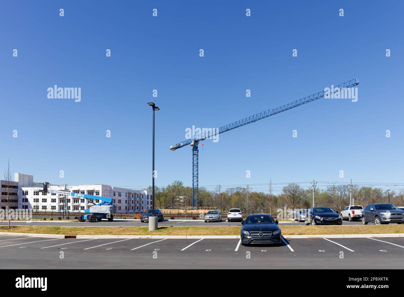 CHARLOTTE, NC-5. MÄRZ 2023: Bezirk Noda. Großer blauer Baufahrkran, eingerahmt an einem blauen Himmel. Kleine Hubgerüste nach links. Stockfoto