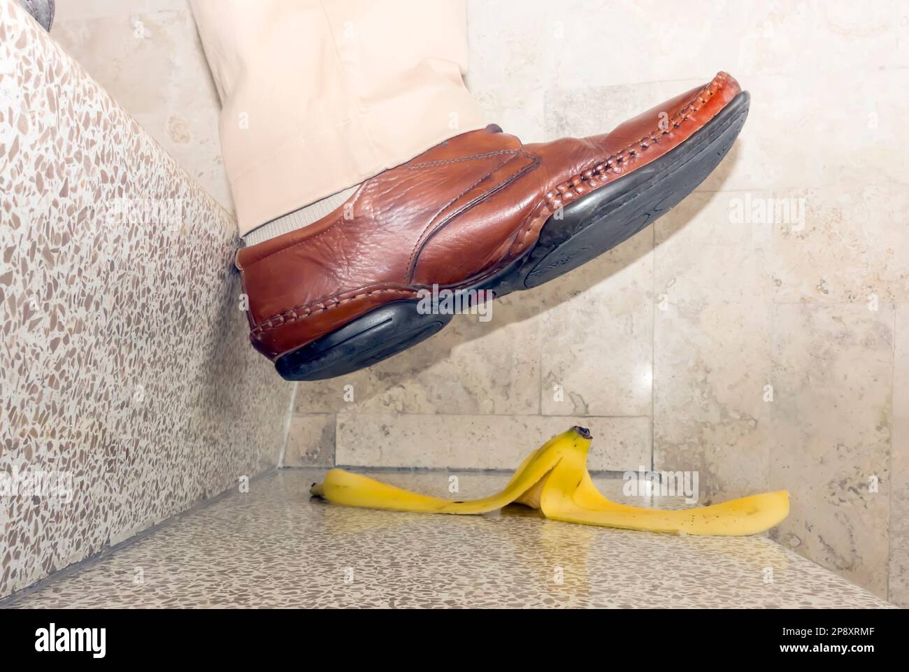 Der Fuß tritt gleich auf die Bananenhaut auf der Treppe Stockfoto
