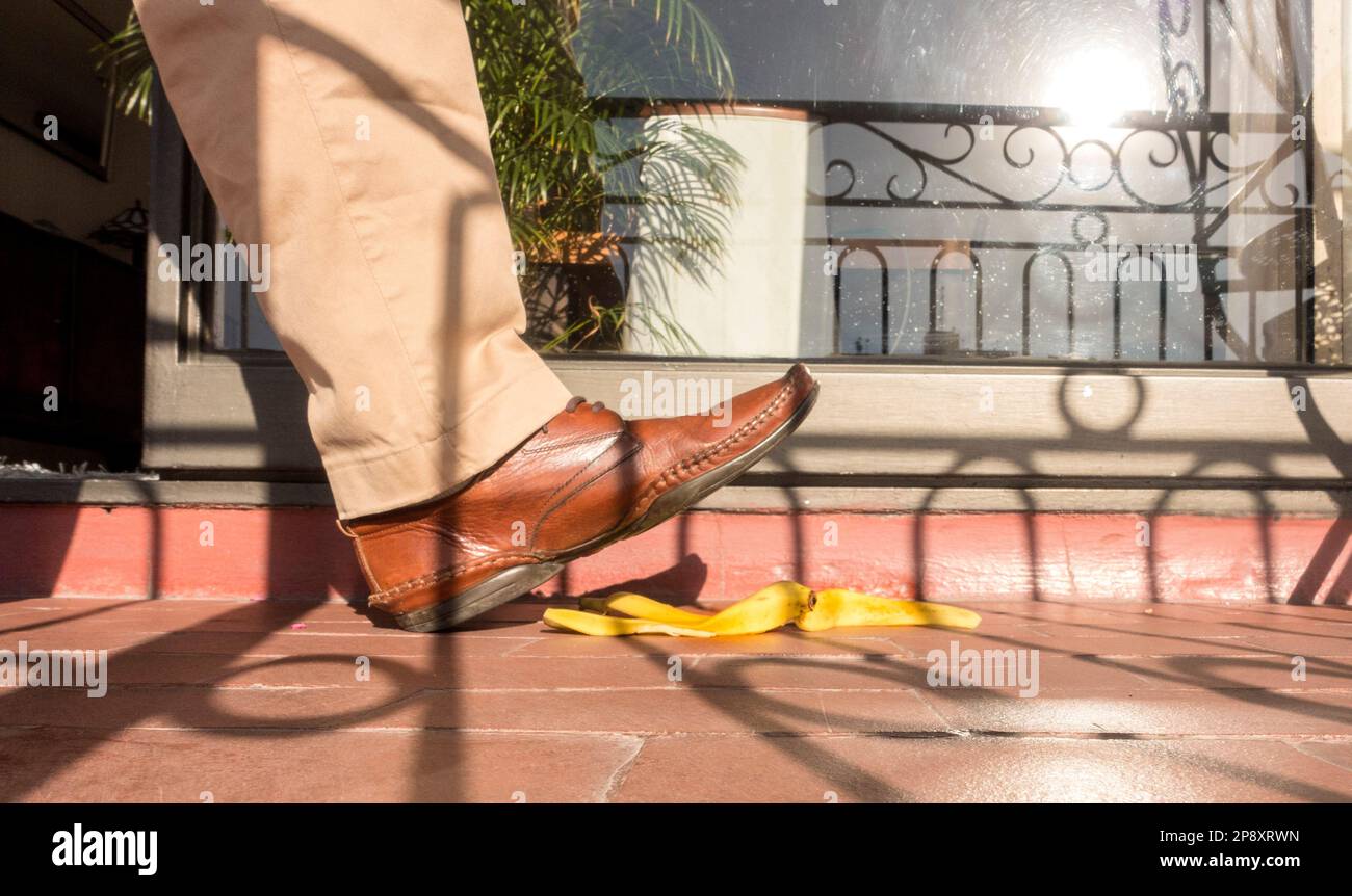 Der Fuß tritt gleich auf die Bananenhaut auf der Treppe Stockfoto