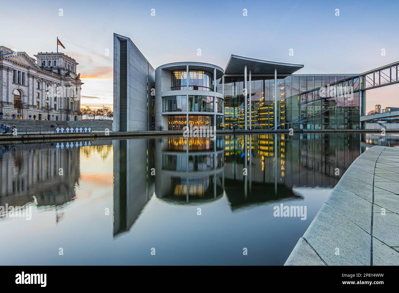 Regierungsbezirk in Berlin mit der Spree am Abend. Reichstag und Paul Löbe Haus mit Reflexion auf der Wasseroberfläche bei Sonnenuntergang. Stockfoto