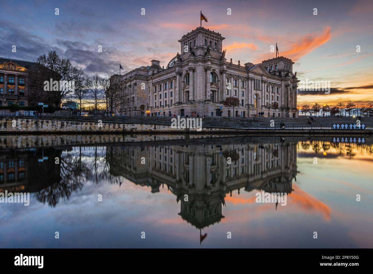 Blick auf das parlamentsgebäude in Berlin. Regierung in Deutschland am Platz der Republik. Spree mit Sonnenuntergangsreflexion. Beleuchtetes Gebäude Stockfoto