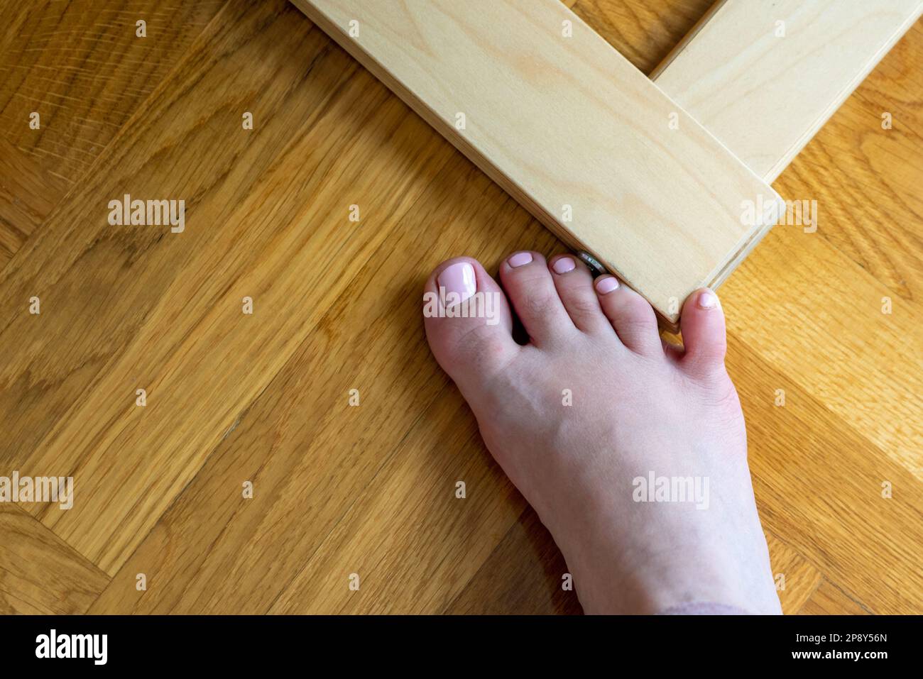 Frau schlug mit dem kleinen Zeh auf die Möbel. Zwischenfall zu Hause. Verletzung des kleinen Fingers des Fußes Stockfoto