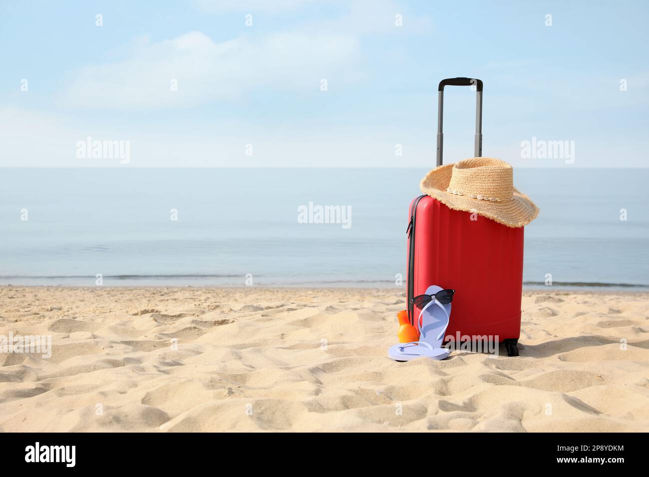 Roter Koffer mit Strandgegenständen am Sandstrand, Platz für Text Stockfoto