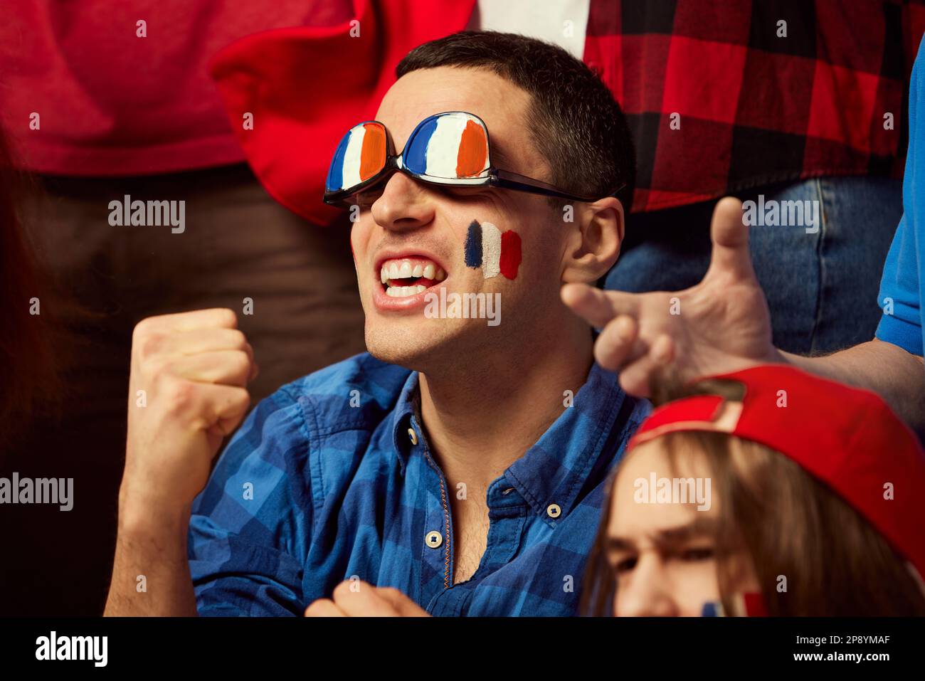 Fußball- und Fußballfans, die ihre französische Lieblingsmannschaft  emotional aufheitern. Mann mit Brille in den Farben der Landesflagge.  Fröhliche Emotionen, Siegerspiel Stockfotografie - Alamy