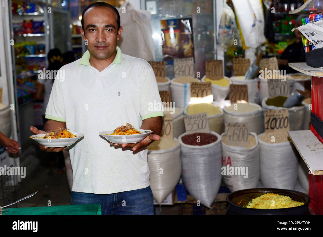 Plov ist das Nationalgericht Usbekistans. Ein usbekischer Mann hält einen Teller traditionellen Plov in einem kleinen Restaurant in Bukhara, Usbekistan. Stockfoto