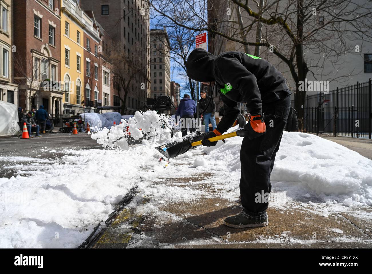 Filmcrew-Mitarbeiter schaufeln gefälschten Schnee an einem Filmset entlang der 82. Street in der Upper East Side von New York City. Stockfoto