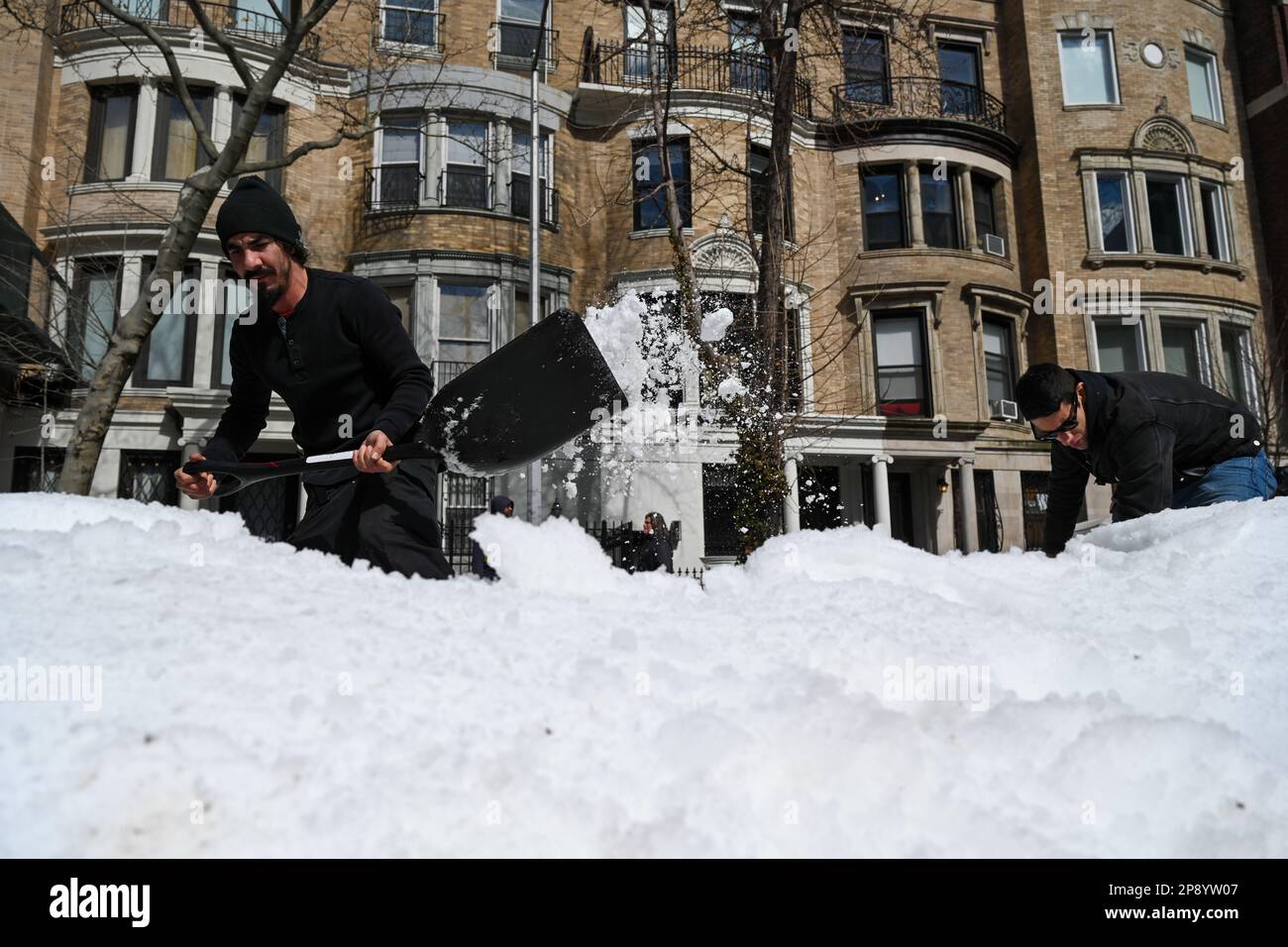 Filmcrew-Mitarbeiter schaufeln gefälschten Schnee an einem Filmset entlang der 82. Street in der Upper East Side von New York City. Stockfoto