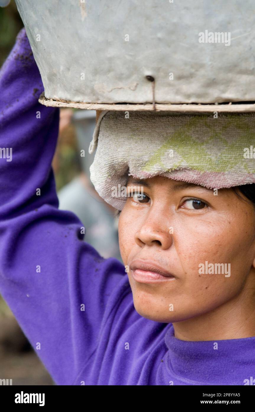 Eine Arbeiterin, die eine Last auf dem Kopf trägt. Ubud, Bali, Indonesien Stockfoto