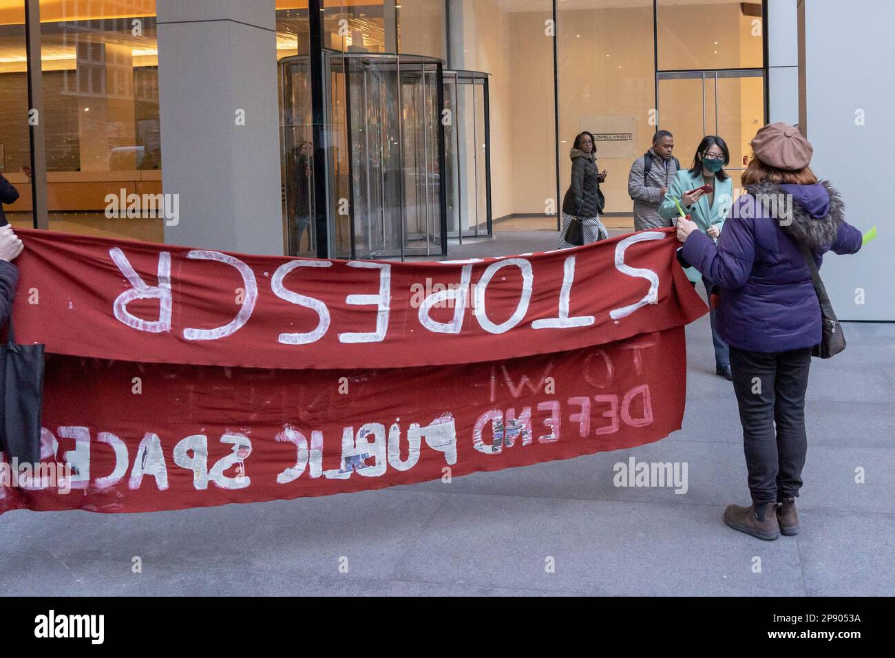 NEW YORK, NEW YORK - MÄRZ 09: Demonstranten mit Schildern und Bannern, während Menschen das Gebäude der New York City Büros von JPMorgan Chase & Co. Verlassen während eines Protests gegen den geplanten Cop City, der am 09. März 2023 in einem Atlanta Wald in New York City gebaut wurde. COP City, eine riesige Polizeiausbildungseinrichtung, die auf einem Waldgebiet im Raum Atlanta, Georgia, im Bau ist, ist zu einem Schwerpunkt der Demonstrationen geworden, die der Entwicklung in einem der unberührtesten Wälder des Bundesstaates entgegenstehen. Das $90-Millionen-Dollar-Ausbildungszentrum soll die Polizei in militarisierter städtischer Kriegsführung ausbilden. Stockfoto