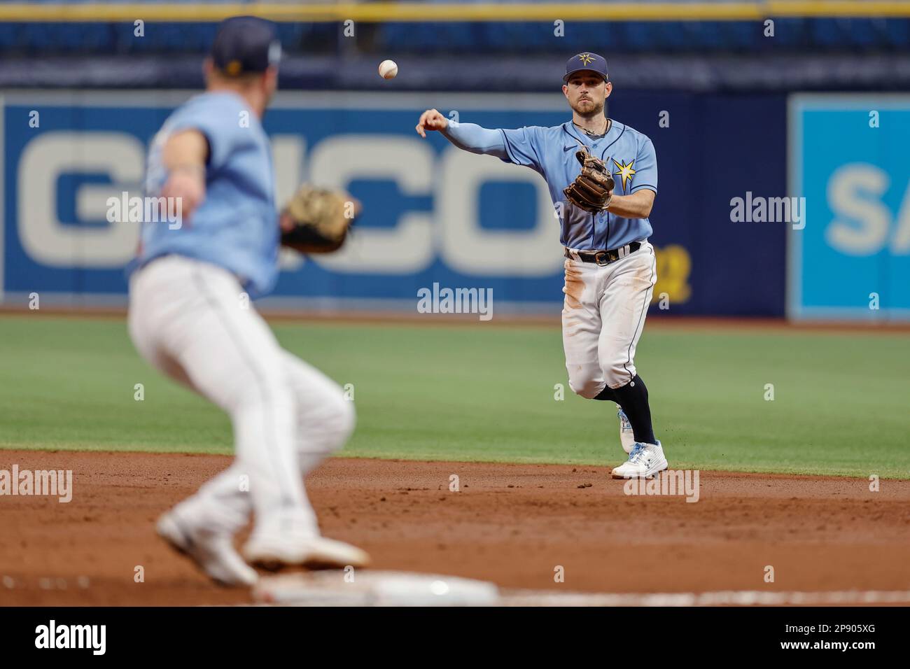 Tampa Bay strahlt den zweiten Baseman Brandon Lowe (8) aus und wirft während eines MLB-Frühjahrstrainings gegen den ersten Baseman Luke Raley (55) Stockfoto