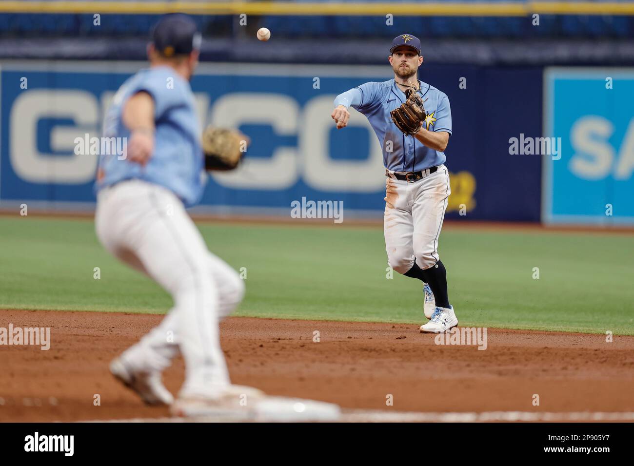 Tampa Bay strahlt den zweiten Baseman Brandon Lowe (8) aus und wirft während eines MLB-Frühjahrstrainings gegen den ersten Baseman Luke Raley (55) Stockfoto