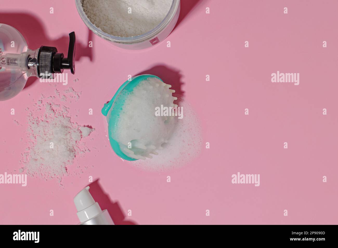 Haarbürste für Kopfhautmassage mit Schaumstoff und Haarreinigungsprodukte auf pinkfarbenem Hintergrund mit rauen Schatten Stockfoto