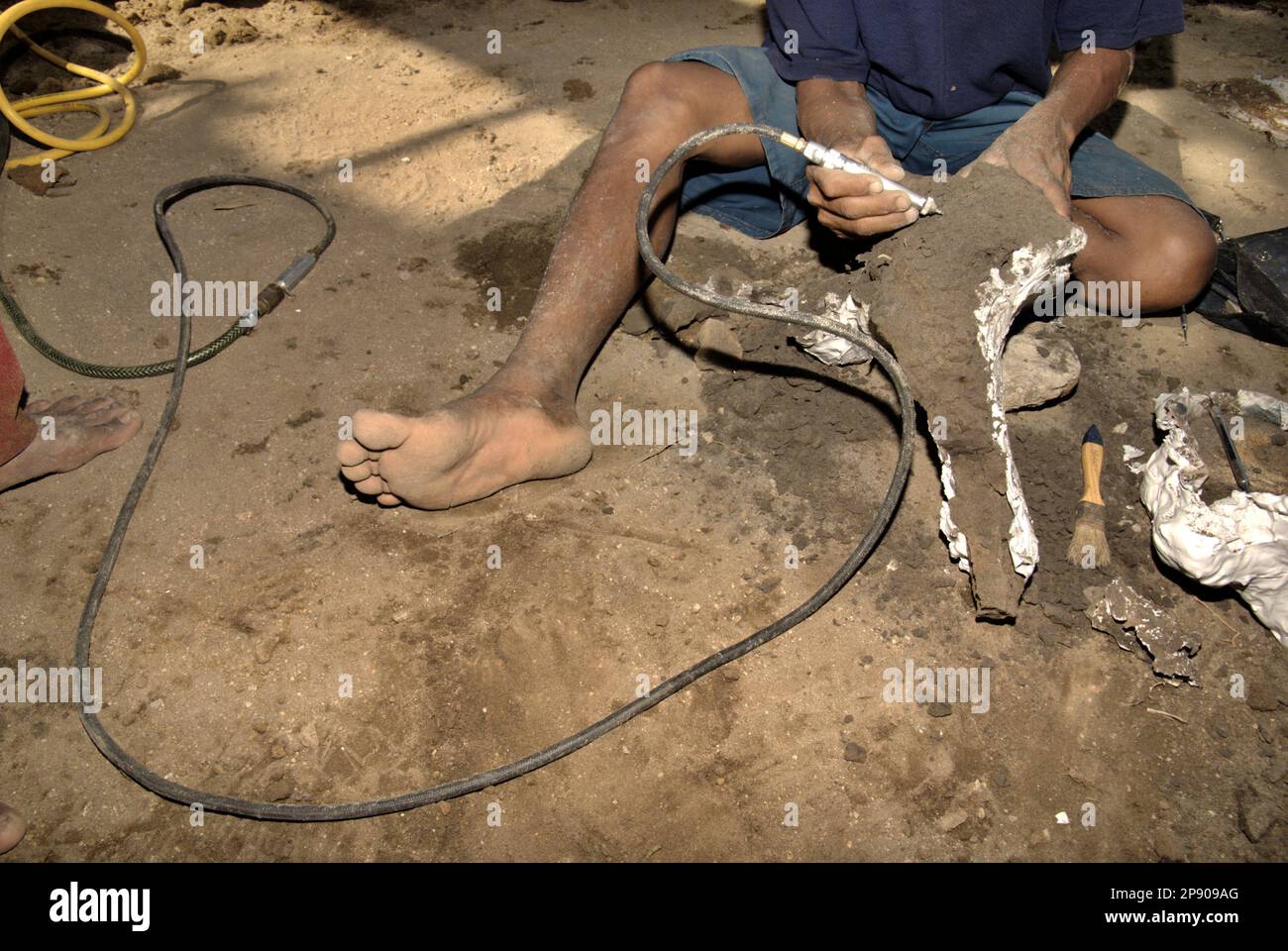 Ein Dorfbewohner benutzt einen Reiniger, da er mit einem versteinerten Knochen einer ausgestorbenen Elefantenart arbeitet, die wissenschaftlich als Elephas hysudrindicus oder allgemein als Blora Elephant bezeichnet wird, an der Ausgrabungsstätte in Sunggun, Mendalem, Kradenan District, Blora Regency, Central Java Province, Indonesien. Das Fossil ist teilweise mit Gips bedeckt, um später zum Geologiemuseum in Bandung, West Java, zu transportieren. Das Team von Wissenschaftlern von Vertebrate Research (Geologische Agentur, indonesisches Ministerium für Energie und mineralische Ressourcen) unter der Leitung von Iwan Kurniawan und Fachroel Aziz entdeckte... Stockfoto