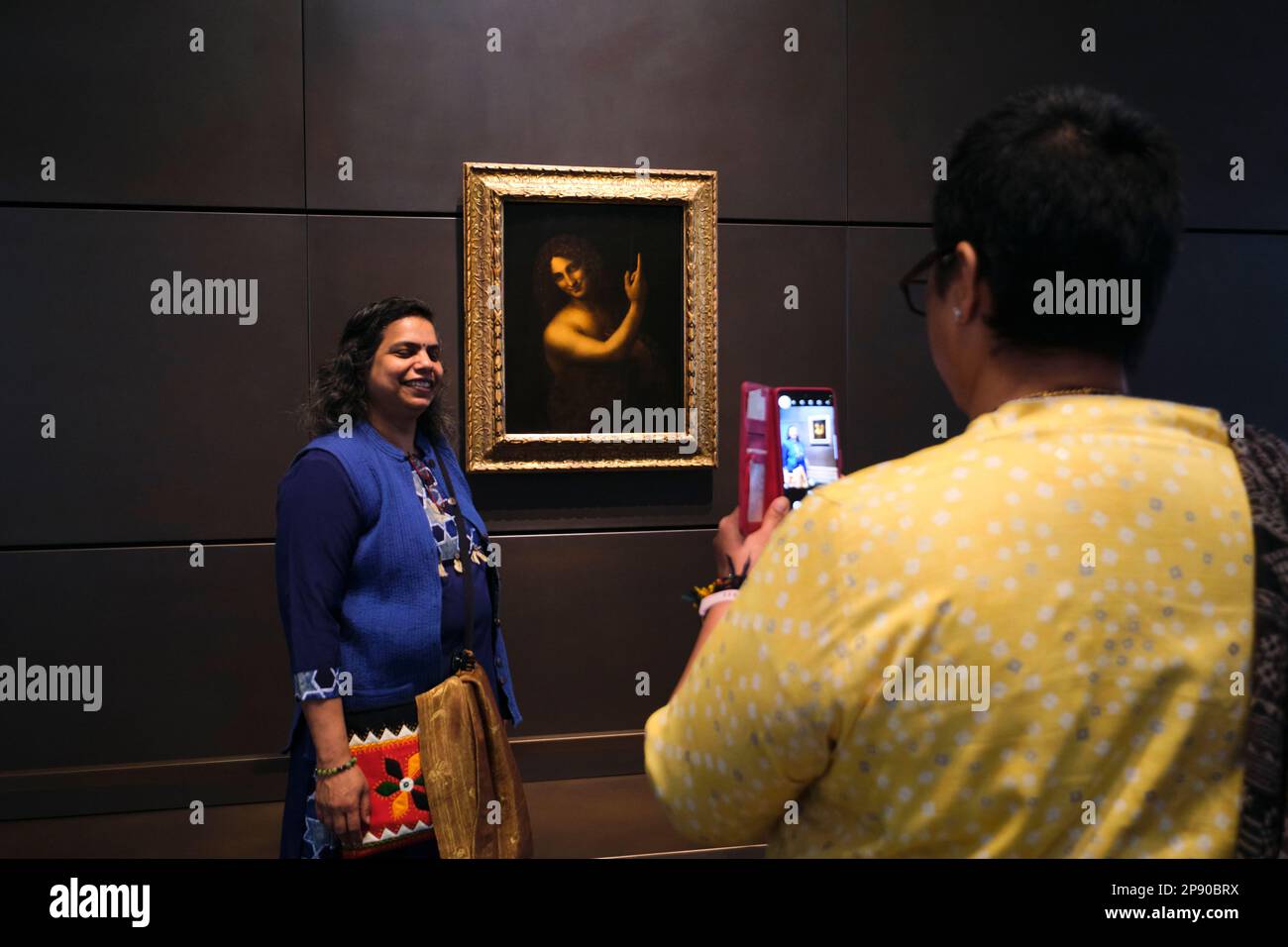 Leute, die Leonardo da Vincis Gemälde Johannes der Täufer genießen. Im Kunstmuseum des französischen Louvre in Abu Dhabi, Vereinigte Arabische Emirate. Stockfoto