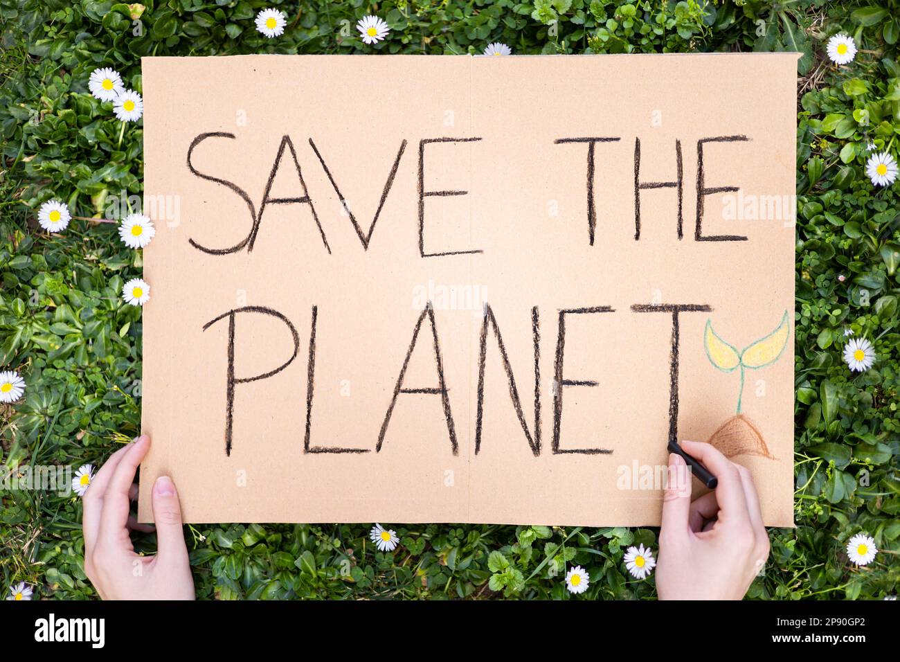 Aktivist schreibt Poster "SAVE THE PLANET" zur Manifestation gegen globale Erwärmung und Erdverschmutzung. Pappbanner zum Protest gegen den Klimawandel. Stockfoto