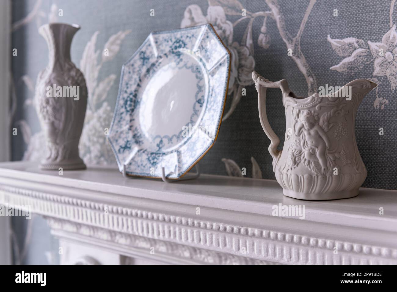 Porzellan und dekorative Platte mit Colefax- und Fowler-Tapete im denkmalgeschützten Landhaus Suffolk im 18. Jahrhundert, UK Stockfoto
