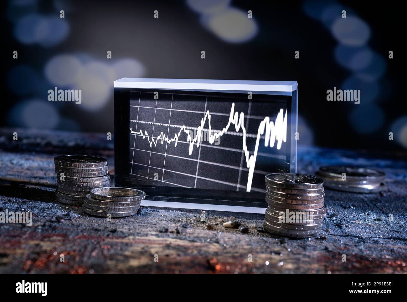 Aktienkarte und Münzen auf Steinboden in dunkler Umgebung mit blauem Licht Stockfoto