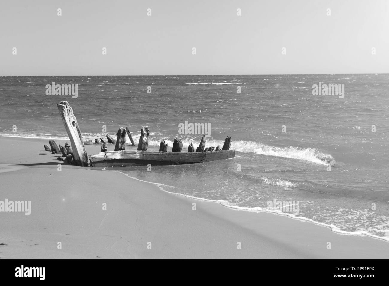 Überreste eines alten Bootes an der Küste. Mit Sand bedeckter Langschwanz aus Holz. Reisen Sie landschaftlich am tropischen Meeresstrand Stockfoto