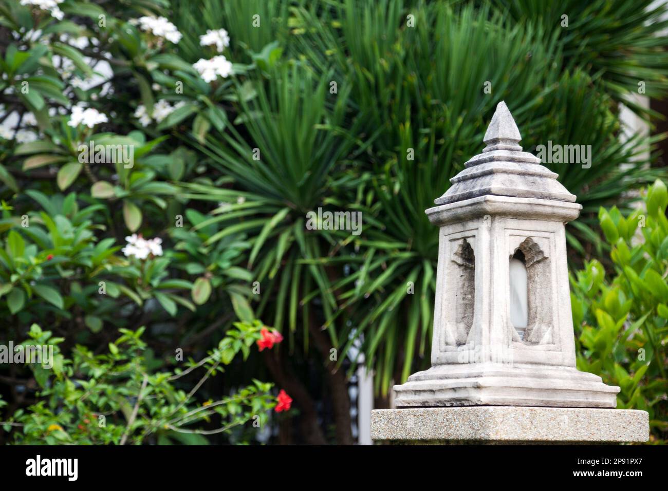 Asiatische traditionelle Outdoor-Steinlaterne in einem tropischen Garten. Geschnitzten Marmor Hof Lampe mit grünen Park Laub Textfreiraum Stockfoto