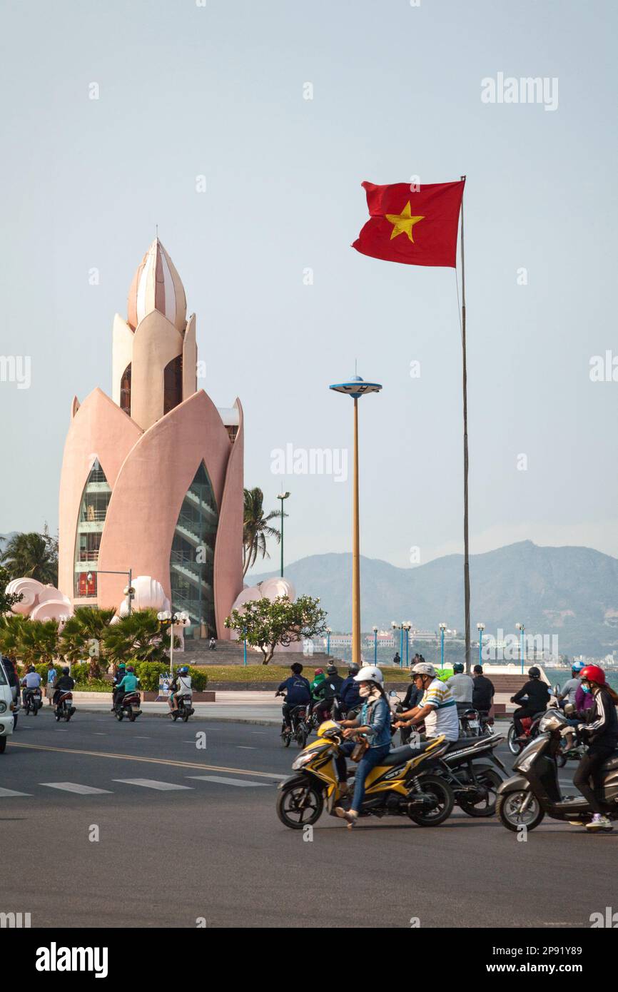 Nha Trang, Vietnam - am 30. März 2018: Die Skyline einer Stadt von Nha Trang mit berühmten Lotus Flower Tower und ein rotes Vietnamesische Flag. Viele Motorräder drivin Stockfoto