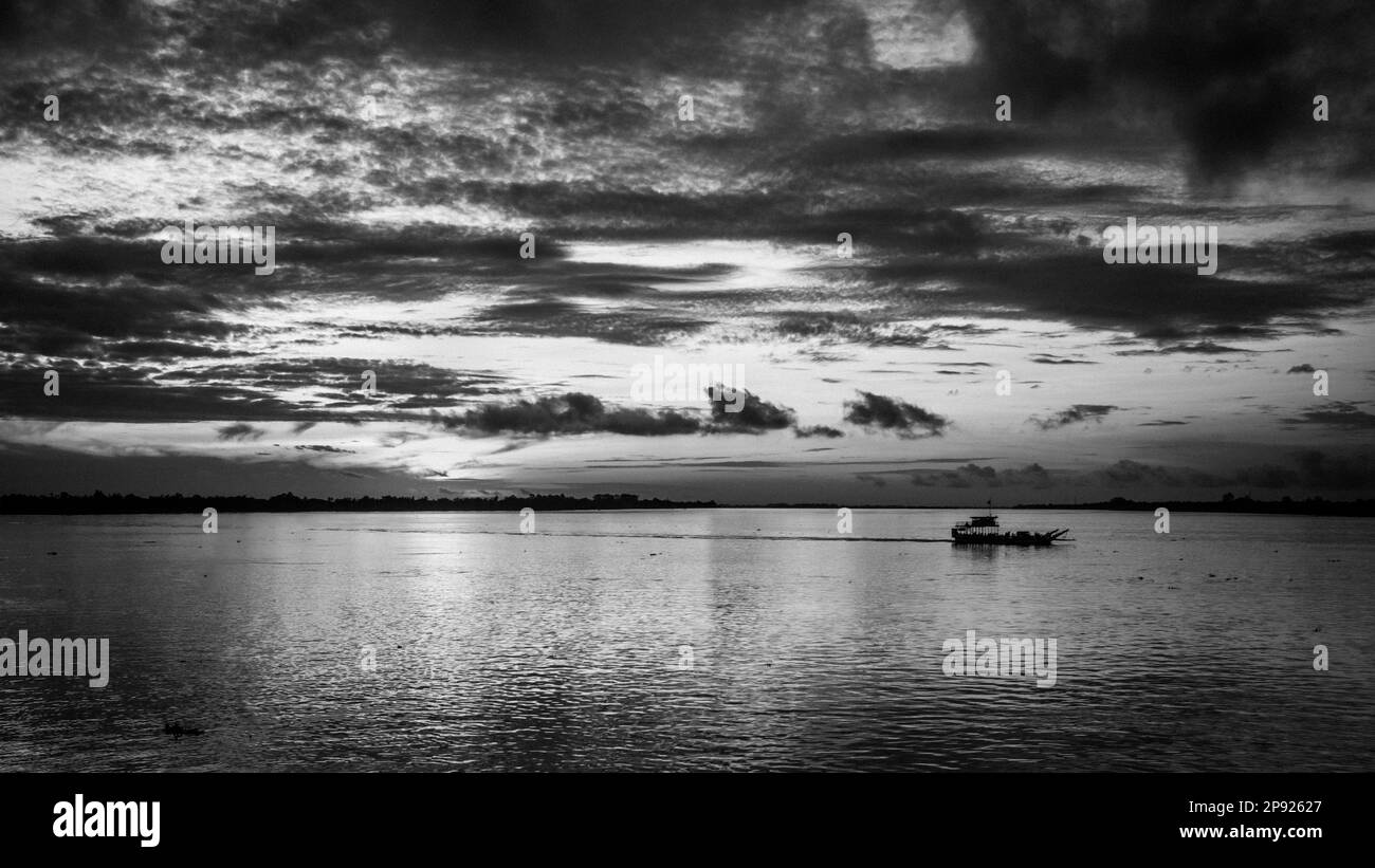 Eine kleine Fähre fährt bei Sonnenaufgang direkt stromabwärts von Phnom Penh in Kambodscha über den Mekong. Stockfoto