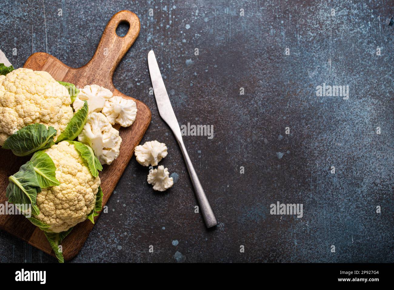 Frischer, organisch geschnittener Blumenkohl auf Holzschneidplatte mit Küchenmesser, fertig zum Kochen, Draufsicht mit Kopierbereich. Vegetarisches Essen, sauberes Essen Stockfoto