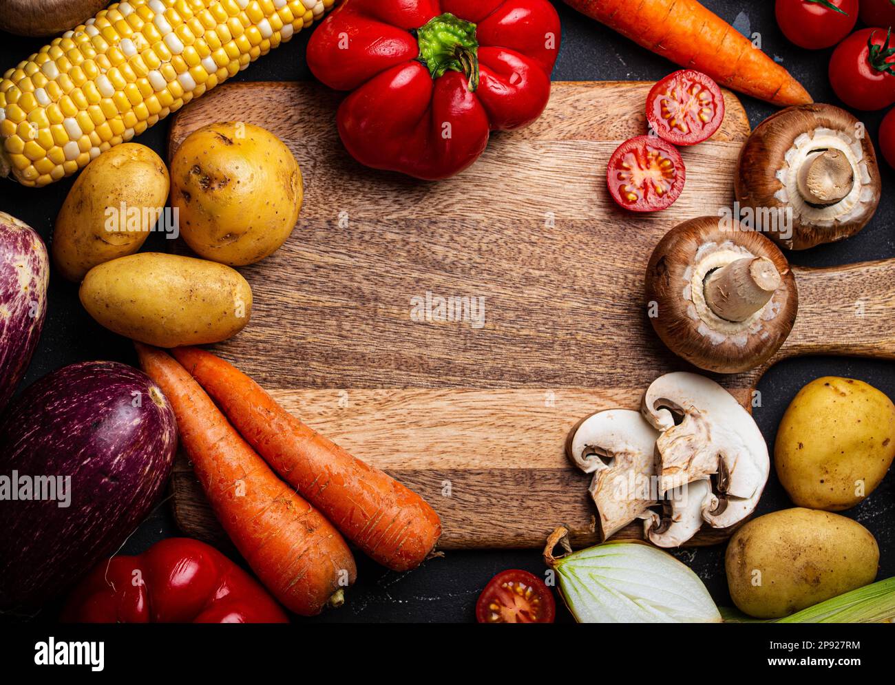 Holzschneidebrett Draufsicht mit verschiedenen rohen Gemüsesorten, Kartoffeln, Tomaten, Pilzen und Zwiebeln für das Abendessen zu Hause. Hintergrund der Kochkunst Stockfoto