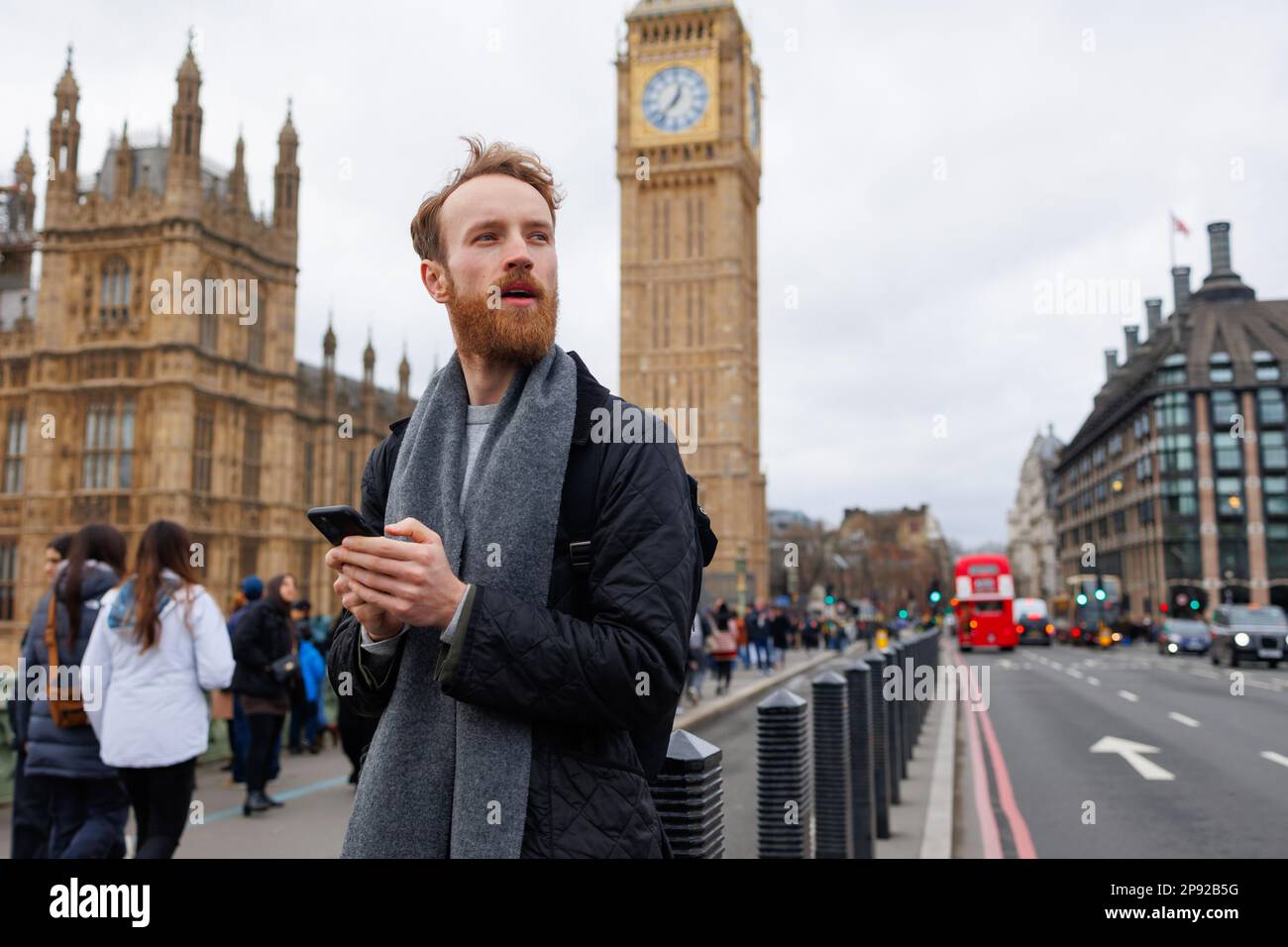 Ein überraschter Mann, der in der Londoner Straße ein Smartphone benutzt Stockfoto