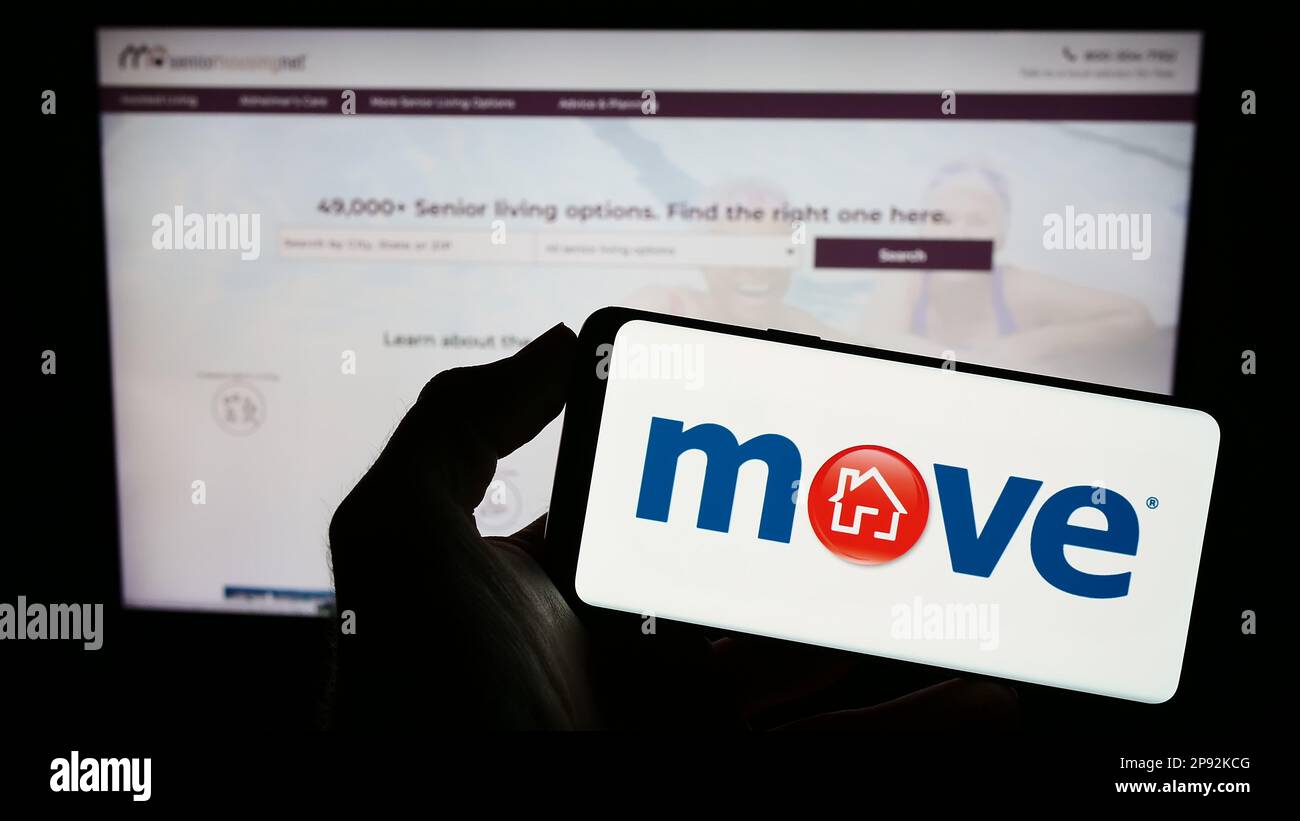 Person, die ein Mobiltelefon mit dem Logo der US-Immobiliengesellschaft Move Inc. Auf dem Bildschirm vor der Unternehmenswebseite hält. Konzentrieren Sie sich auf das Display des Telefons. Stockfoto