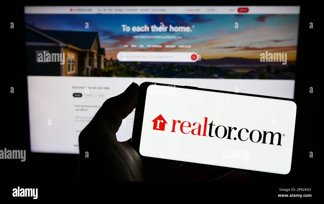 Person, die ein Smartphone mit dem Logo der US-Immobilienplattform Realtor.com (Move Inc.) auf dem Bildschirm vor der Website hält. Konzentrieren Sie sich auf das Display des Telefons. Stockfoto