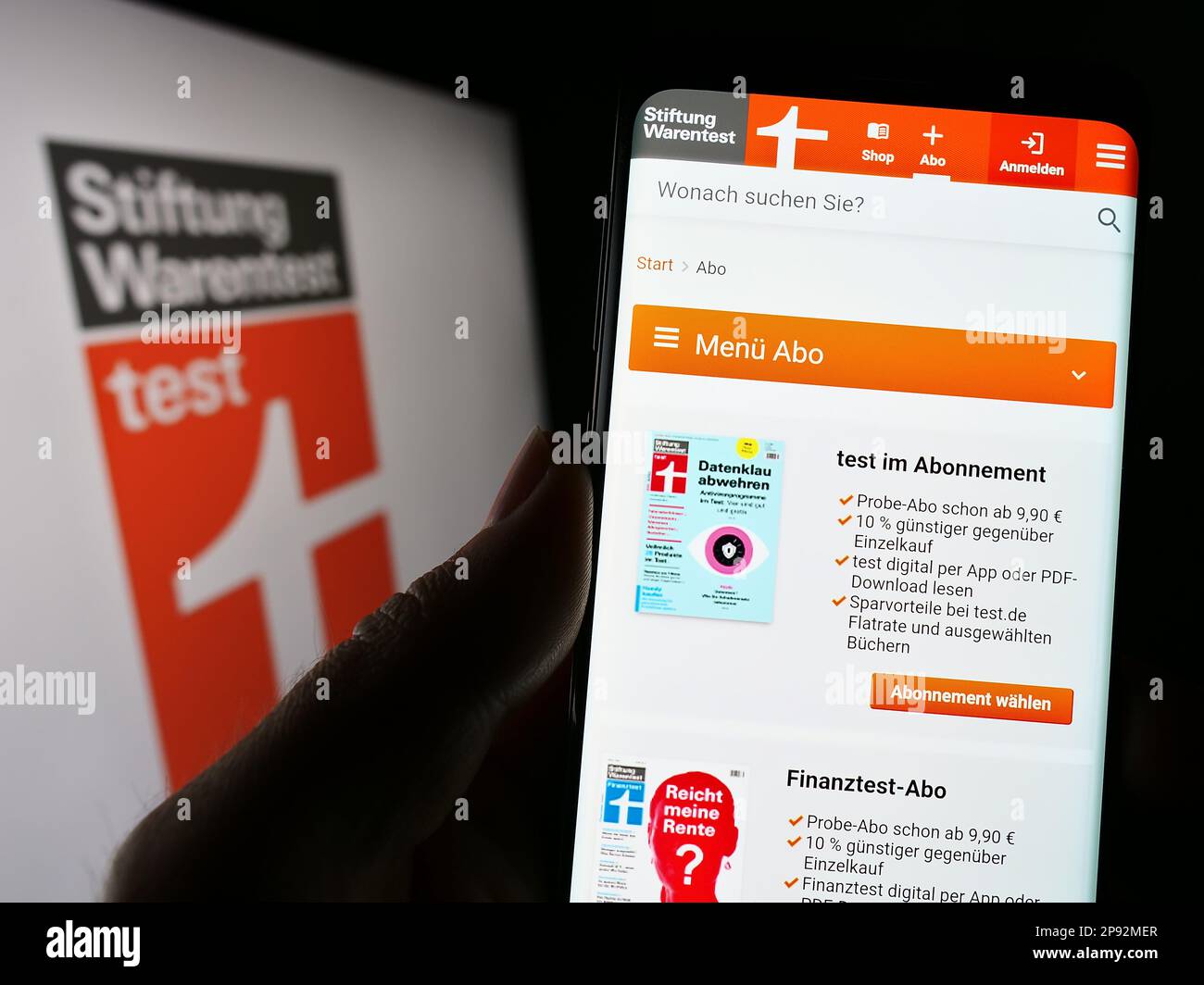 Person mit Smartphone und Webseite der deutschen Verbraucherorganisation Warentest auf dem Bildschirm mit Logo. Konzentrieren Sie sich auf die Mitte des Telefondisplays. Stockfoto