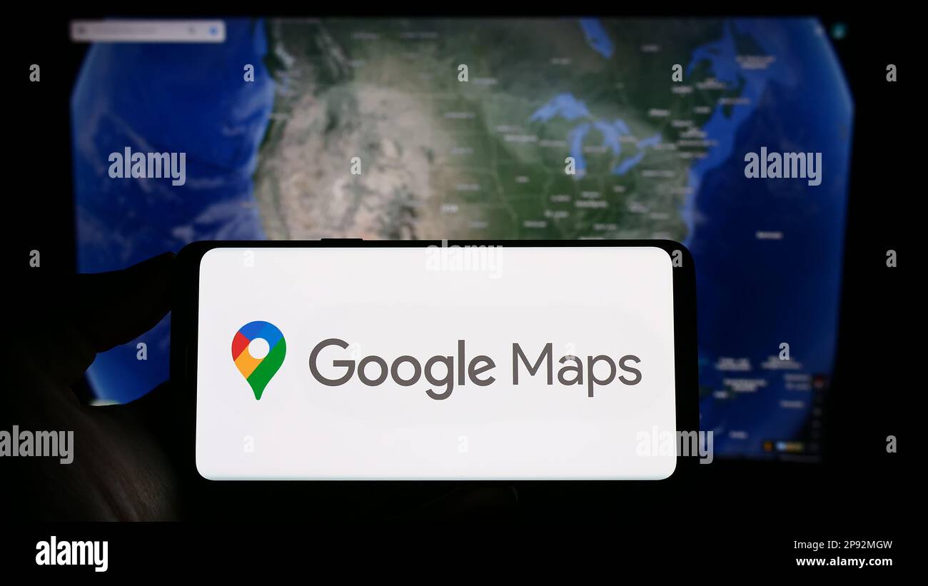 Person, die ein Mobiltelefon mit dem Logo der Web-Mapping-Plattform Google Maps auf dem Bildschirm vor der Webseite hält. Konzentrieren Sie sich auf das Display des Telefons. Stockfoto